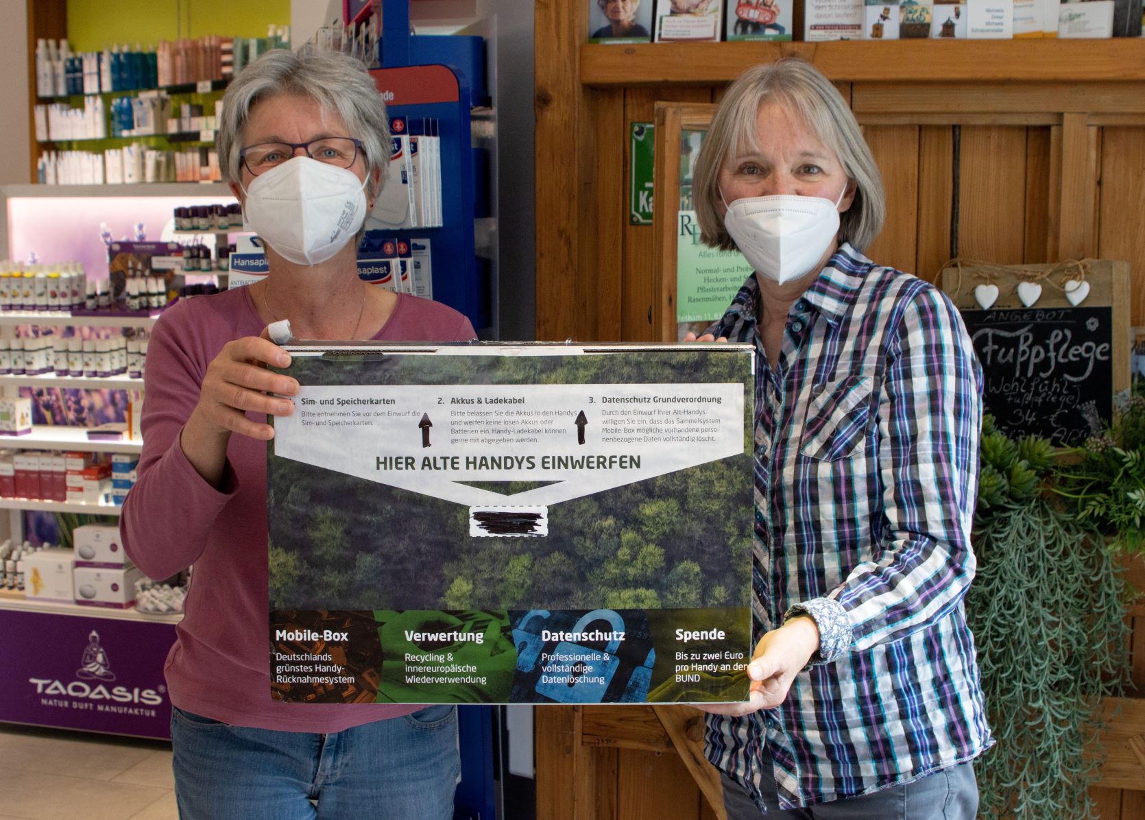P. Ostler und J. Schekatz mit Handy-Sammelbox in der Apotheke